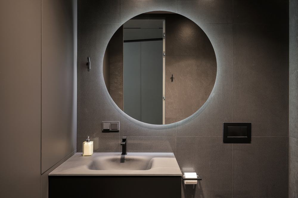 large round mirror in dark bathroom.
